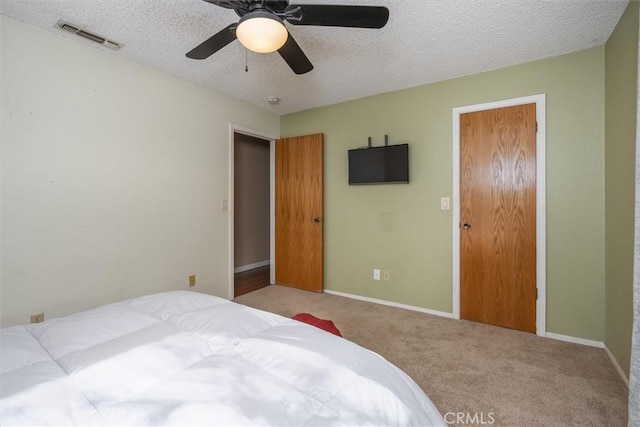 carpeted bedroom featuring a ceiling fan, baseboards, visible vents, and a textured ceiling