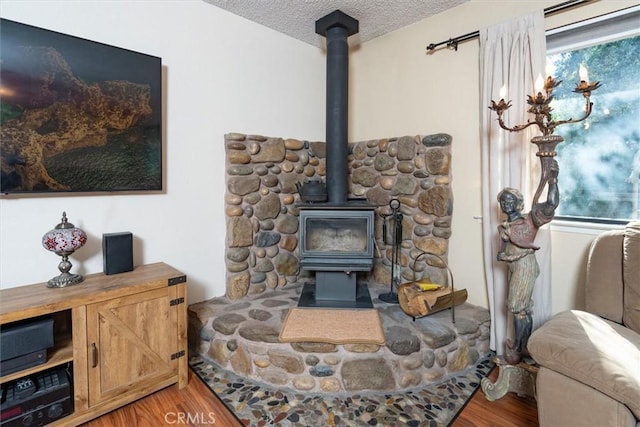 details featuring a wood stove, a textured ceiling, and wood finished floors