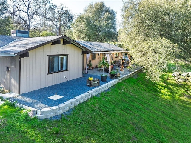 back of house with a patio area, a shingled roof, and a lawn