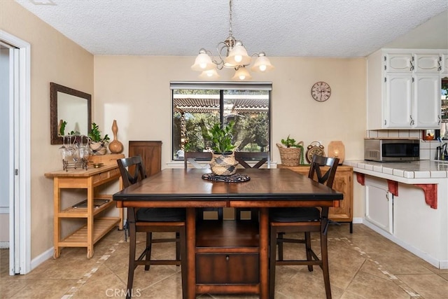 dining room featuring a textured ceiling, light tile patterned floors, baseboards, and an inviting chandelier