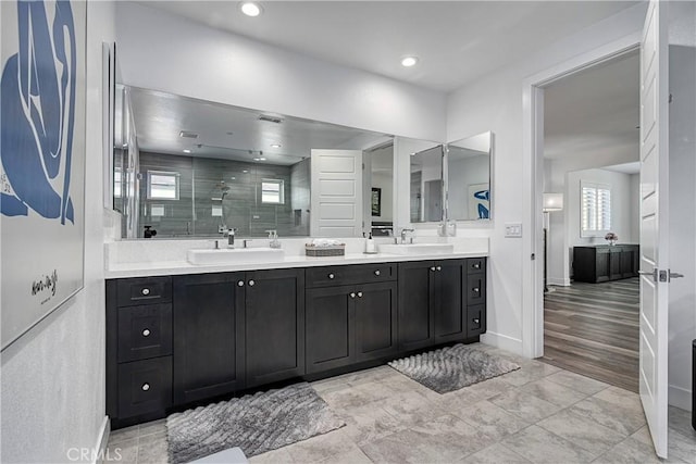 full bathroom with double vanity, a shower stall, and a sink