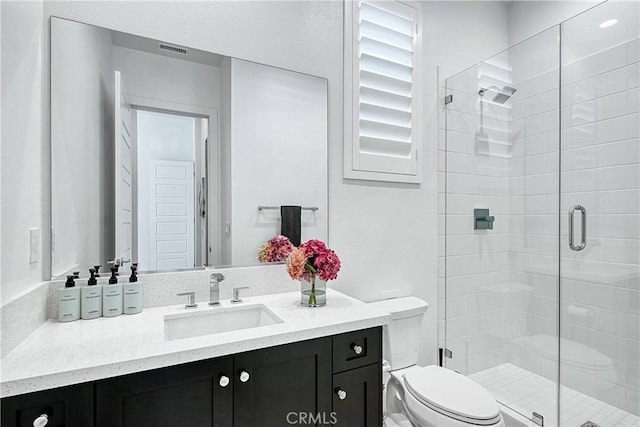 full bathroom featuring toilet, a stall shower, vanity, and visible vents