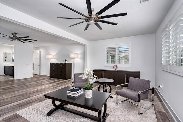 living room featuring baseboards, visible vents, a ceiling fan, and wood finished floors