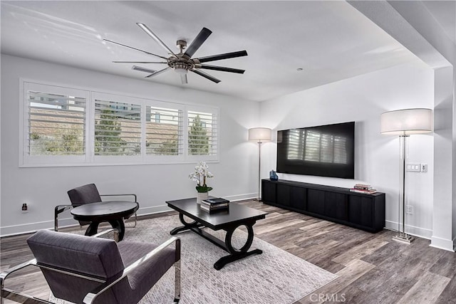 living area featuring a ceiling fan, baseboards, and wood finished floors