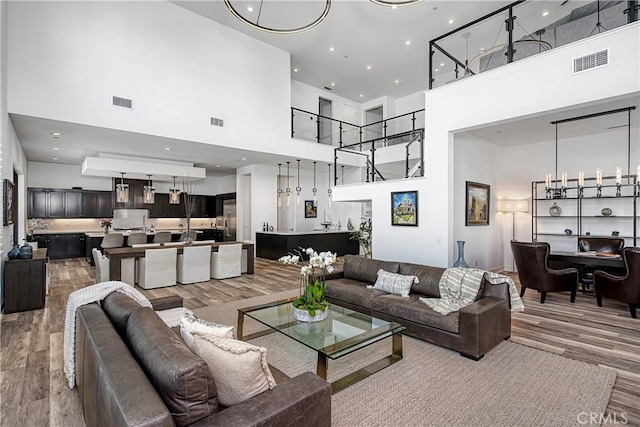 living area with light wood finished floors, a towering ceiling, and visible vents