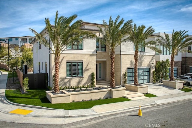 view of front of property with concrete driveway, an attached garage, and stucco siding