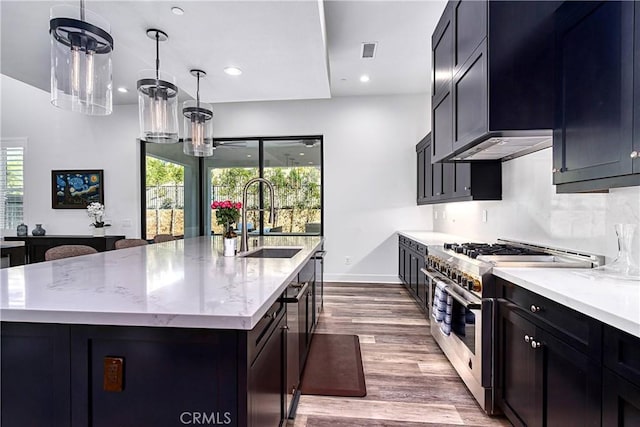 kitchen featuring visible vents, an island with sink, high end stainless steel range oven, light stone countertops, and a sink