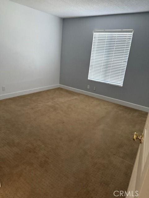 empty room with light carpet, a textured ceiling, and baseboards