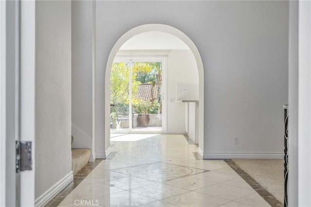 doorway with marble finish floor, baseboards, and arched walkways