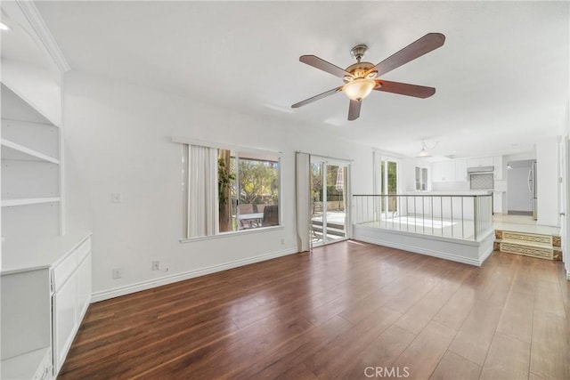 empty room with ceiling fan, baseboards, and wood finished floors