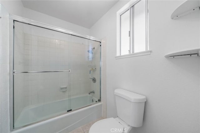 bathroom with toilet, enclosed tub / shower combo, and tile patterned floors