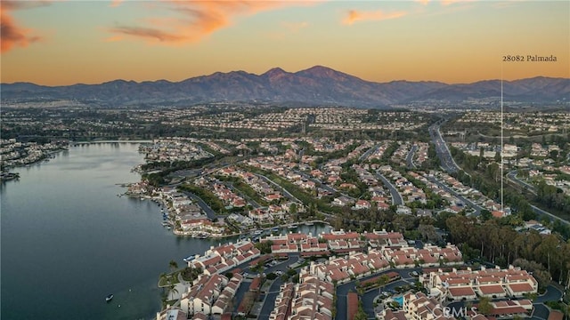 aerial view at dusk featuring a water and mountain view