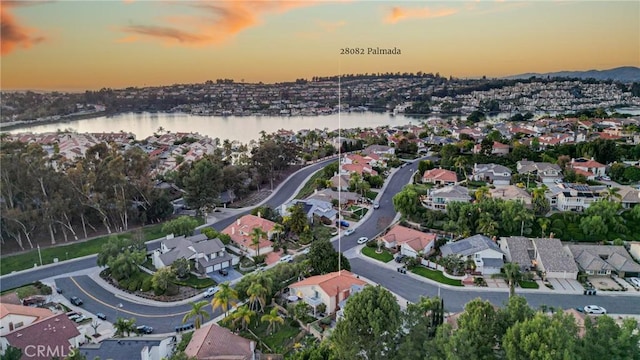 aerial view at dusk featuring a water view and a residential view