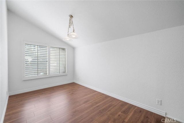 spare room with lofted ceiling, baseboards, and dark wood-style flooring