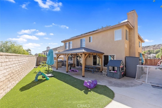 rear view of property featuring a patio, a playground, a fenced backyard, a gazebo, and stucco siding