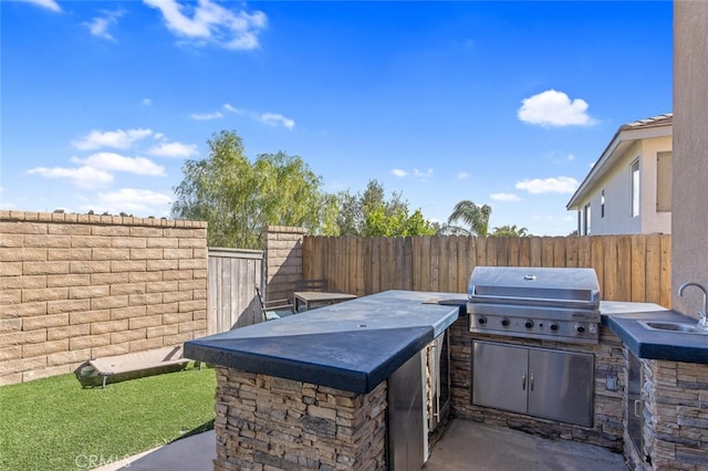 view of patio / terrace featuring a sink, exterior kitchen, grilling area, and a fenced backyard