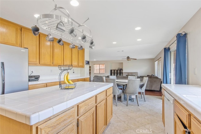 kitchen with ceiling fan, tile counters, open floor plan, and dishwasher