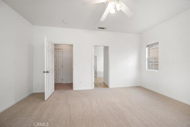 unfurnished bedroom with baseboards, visible vents, light colored carpet, ceiling fan, and ensuite bathroom