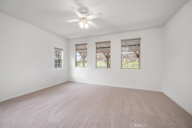 unfurnished room featuring a ceiling fan, light carpet, and baseboards