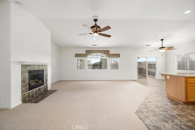 unfurnished living room featuring ceiling fan, a wealth of natural light, and a tile fireplace