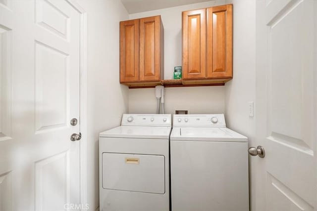 clothes washing area with cabinet space and separate washer and dryer