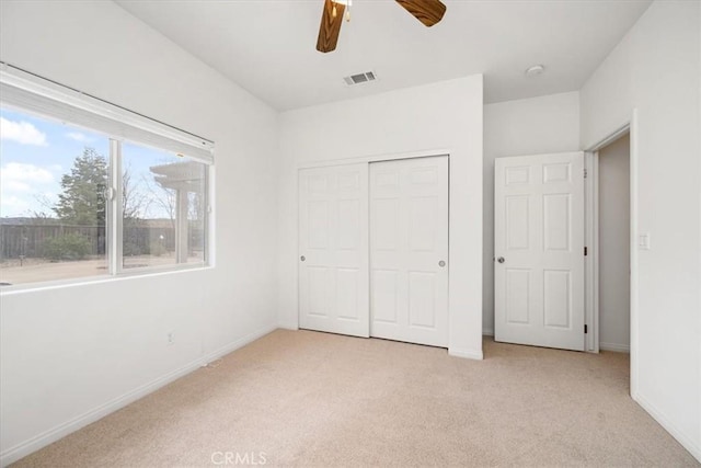 unfurnished bedroom featuring light carpet, baseboards, visible vents, and a closet