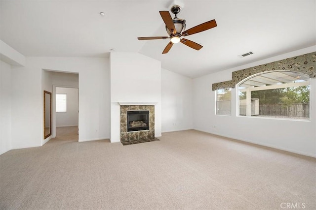 unfurnished living room featuring visible vents, light carpet, vaulted ceiling, ceiling fan, and a tile fireplace