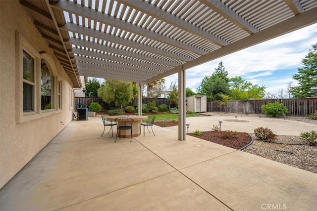 view of patio / terrace with an outbuilding, a shed, outdoor dining space, and a fenced backyard