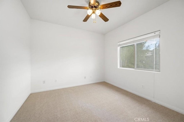 spare room featuring light carpet, ceiling fan, and baseboards