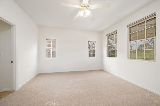 spare room featuring baseboards, ceiling fan, and light colored carpet