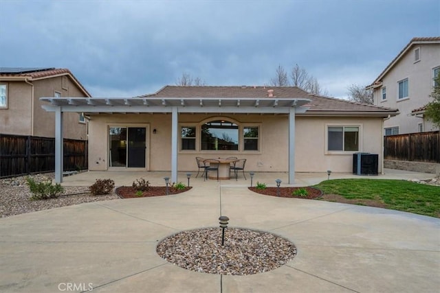 rear view of property featuring fence, a pergola, a patio, and stucco siding