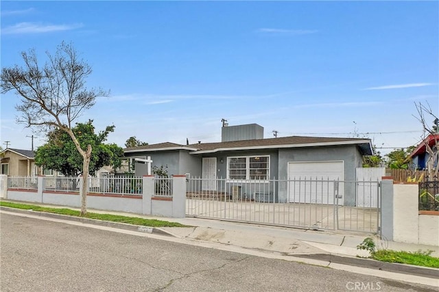 ranch-style house featuring concrete driveway, a fenced front yard, an attached garage, a gate, and stucco siding