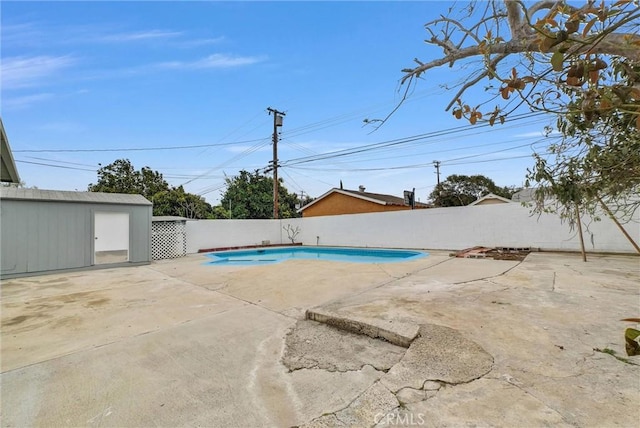 view of pool featuring an outdoor structure, a patio area, a fenced backyard, and a fenced in pool