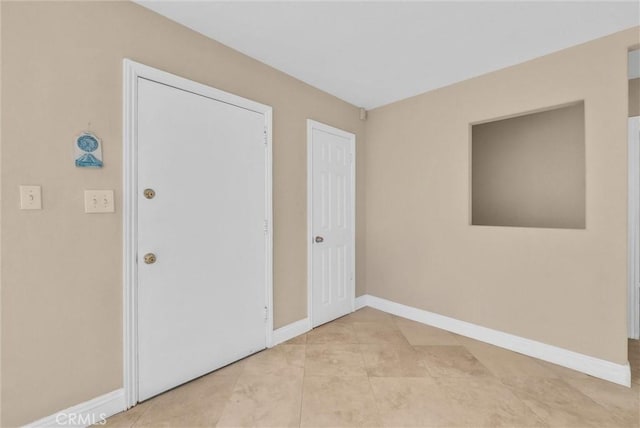 spare room with baseboards and light tile patterned flooring