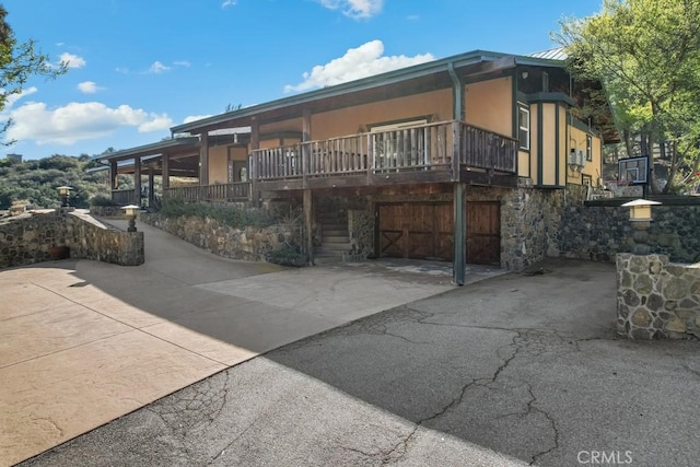 exterior space with stairs, stone siding, driveway, and stucco siding