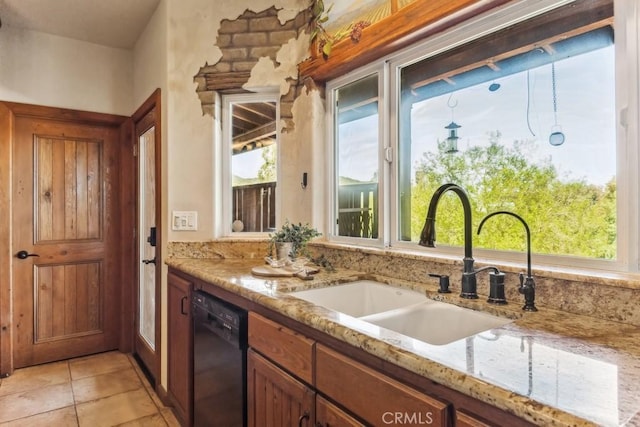 kitchen featuring brown cabinets, light tile patterned floors, a sink, light stone countertops, and dishwasher