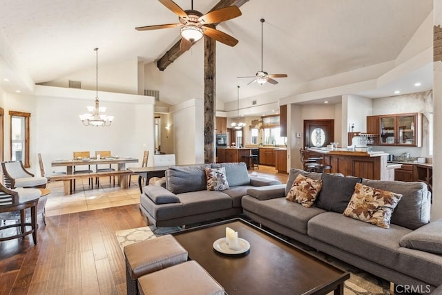 living area featuring dark wood-type flooring, visible vents, high vaulted ceiling, and ceiling fan with notable chandelier