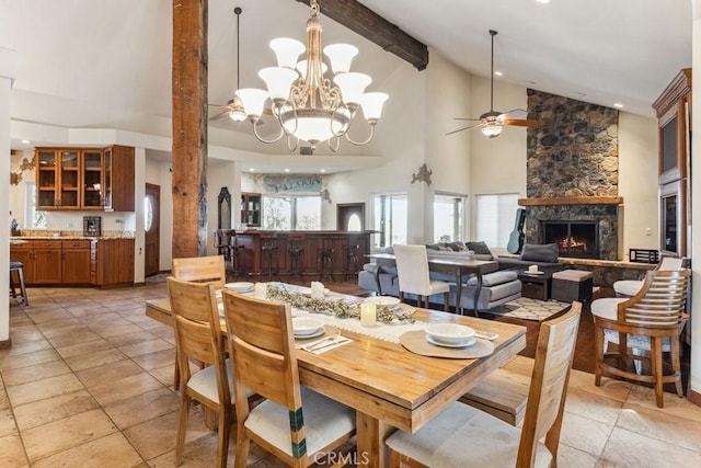 dining room with a fireplace, high vaulted ceiling, beam ceiling, and ceiling fan with notable chandelier