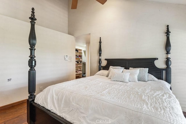 bedroom featuring a high ceiling, wood finished floors, a ceiling fan, a closet, and a walk in closet