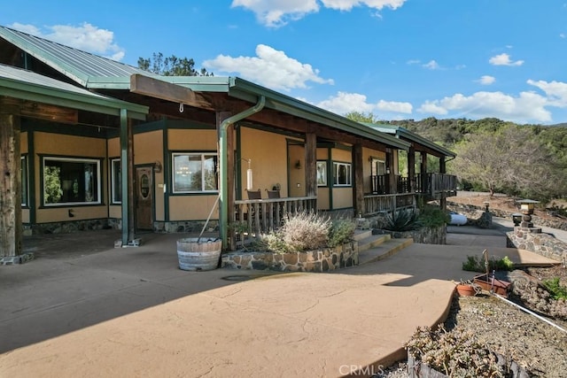 view of front facade with a porch, metal roof, and stucco siding