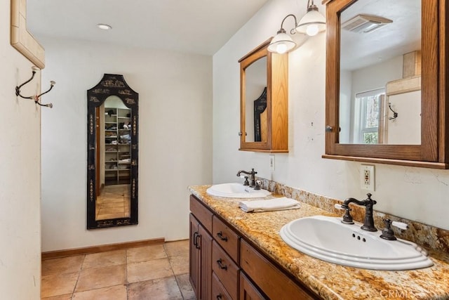 full bathroom with double vanity, baseboards, visible vents, and a sink