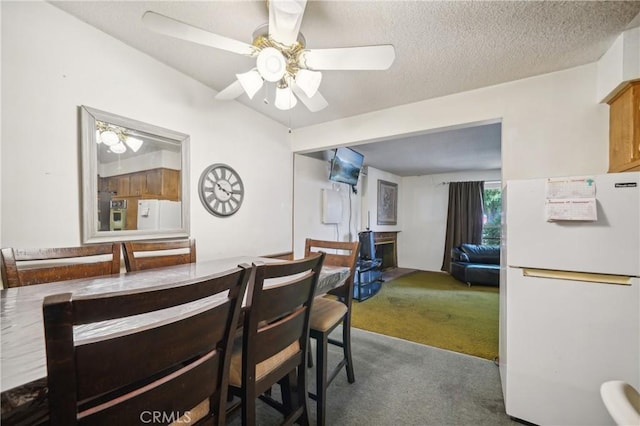 carpeted dining space with a ceiling fan and a textured ceiling