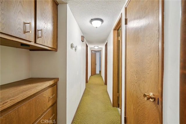 corridor with light colored carpet and a textured ceiling