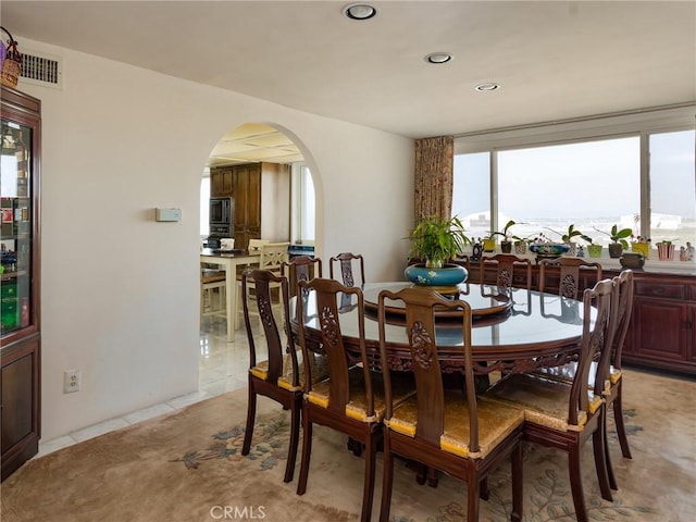 dining space featuring arched walkways, light tile patterned flooring, visible vents, and recessed lighting