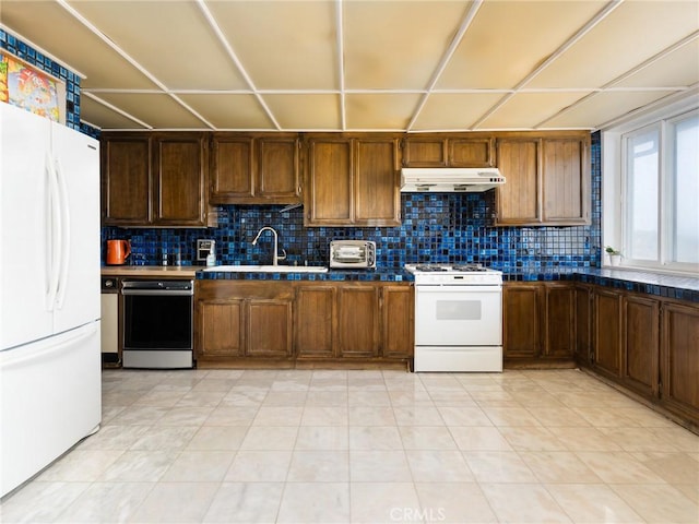 kitchen featuring a toaster, under cabinet range hood, white appliances, a sink, and tasteful backsplash