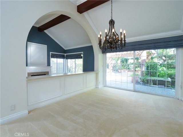 unfurnished room with carpet floors, arched walkways, vaulted ceiling with beams, and a decorative wall