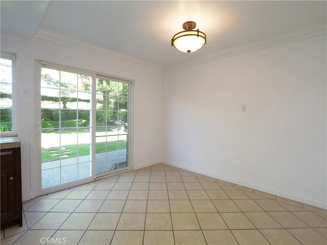 empty room with baseboards, ornamental molding, light tile patterned floors, and a healthy amount of sunlight