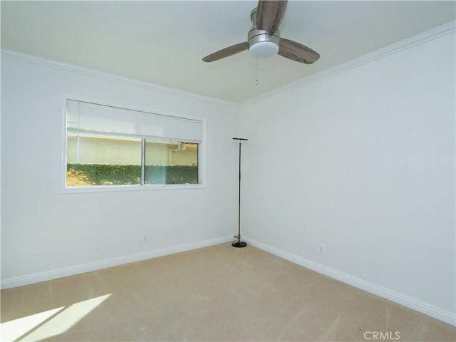 empty room featuring light colored carpet, crown molding, baseboards, and ceiling fan