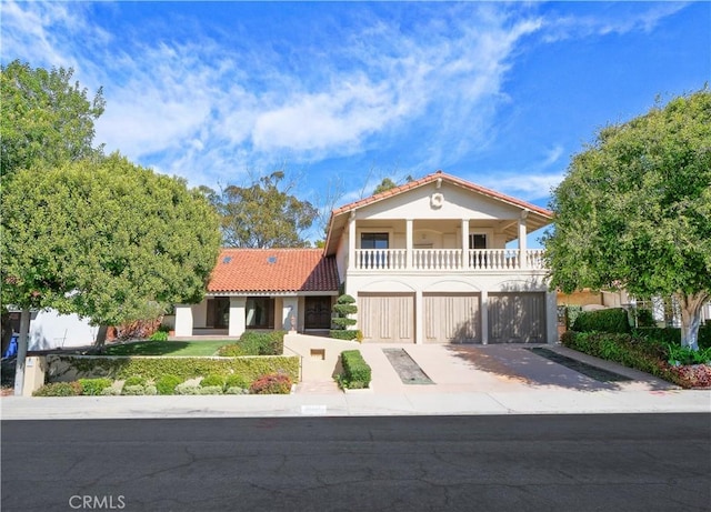 mediterranean / spanish home with driveway, a balcony, stucco siding, and a tiled roof