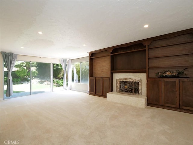 unfurnished living room with light carpet, a warm lit fireplace, and recessed lighting